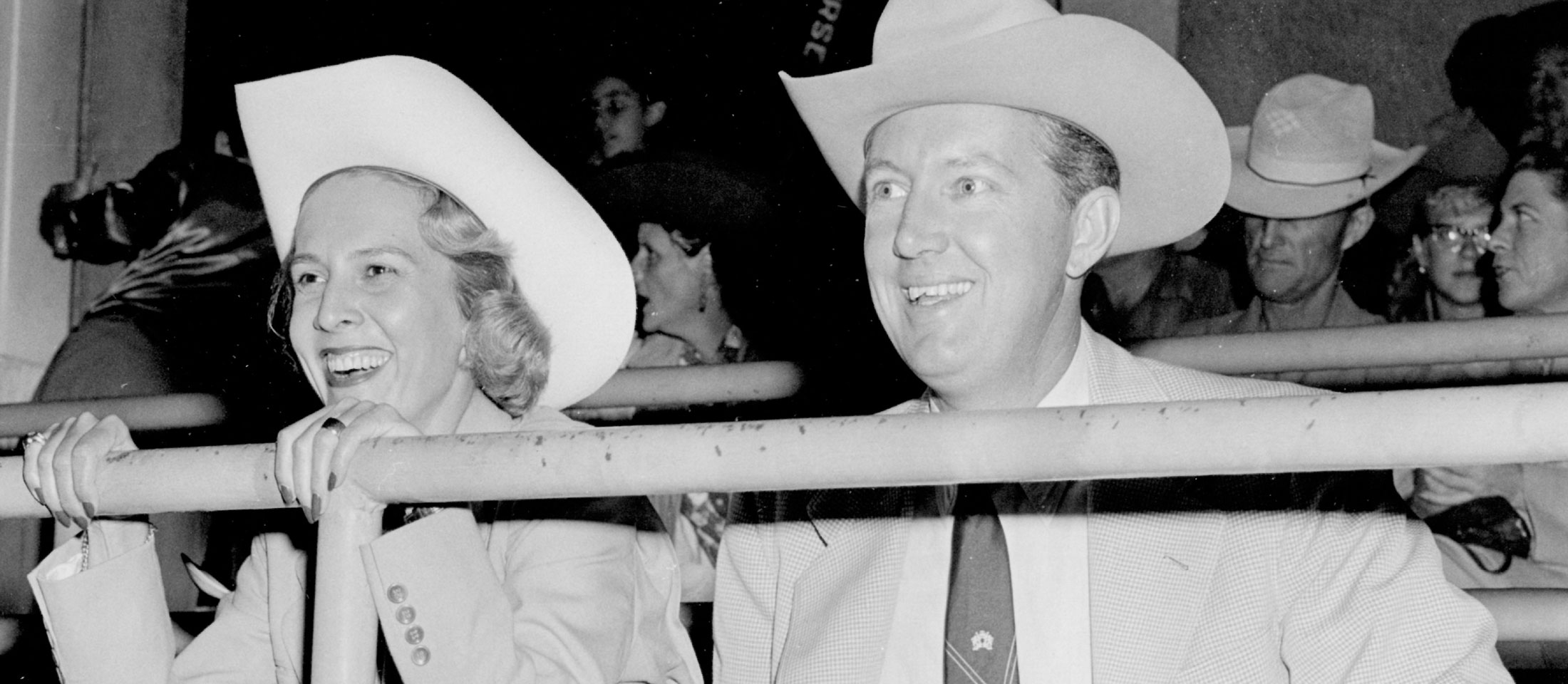 Jane and John Justin smile while cheering at a rodeo.